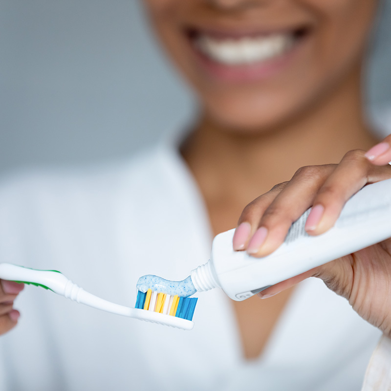 Woman Applying Toothpaste to Toothbrush
