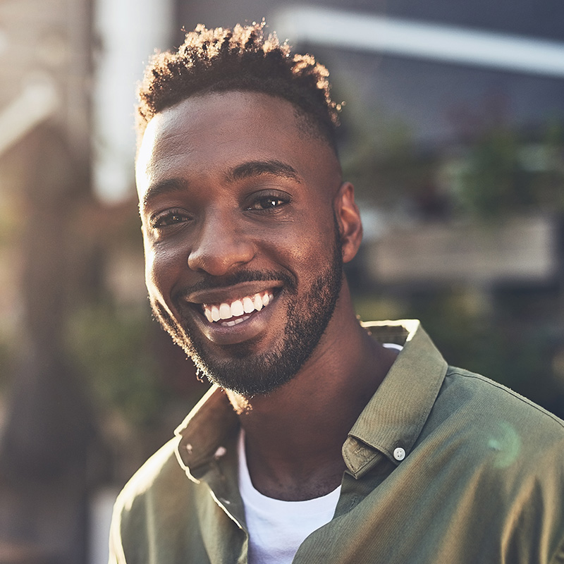 Man Looking at Camera and Smiling in Sunlight Outdoors