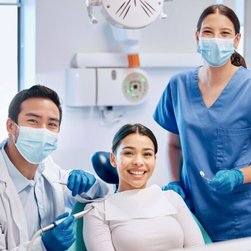 lady in dental chair smiling with dentists on either side